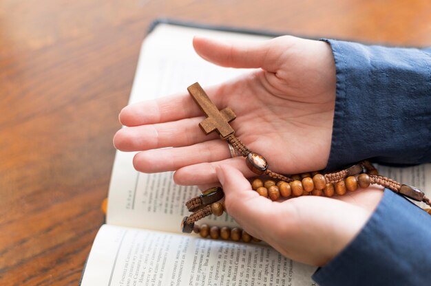 High angle of person holding rosary with holy book open