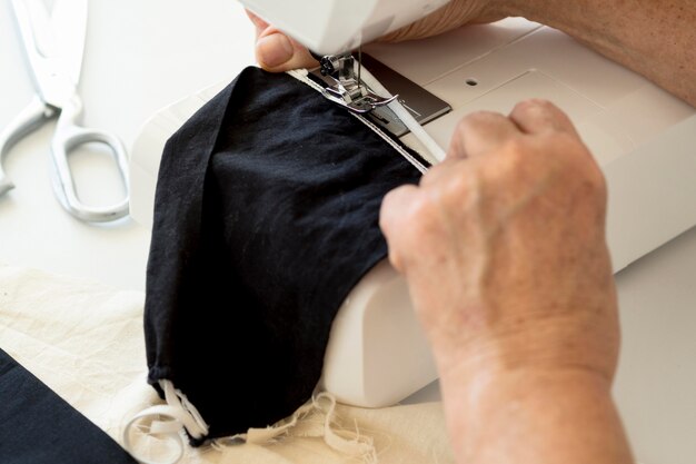 High angle of person using sewing machine for face mask