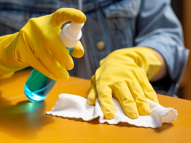 Free photo high angle of person with surgical gloves cleaning surface with alcohol and napkin