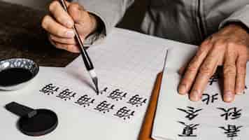 무료 사진 흰 종이에 중국어 기호를 쓰는 높은 각도 사람