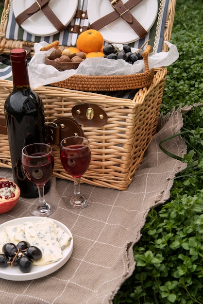 Бесплатное фото Корзина для пикника под большим углом с фруктами и вином