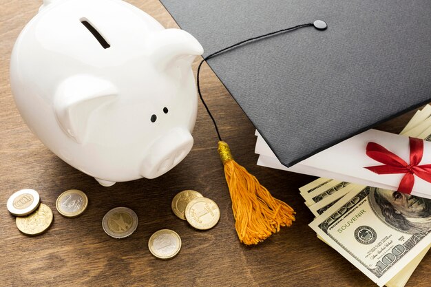 High angle of piggy bank with academic cap and coins