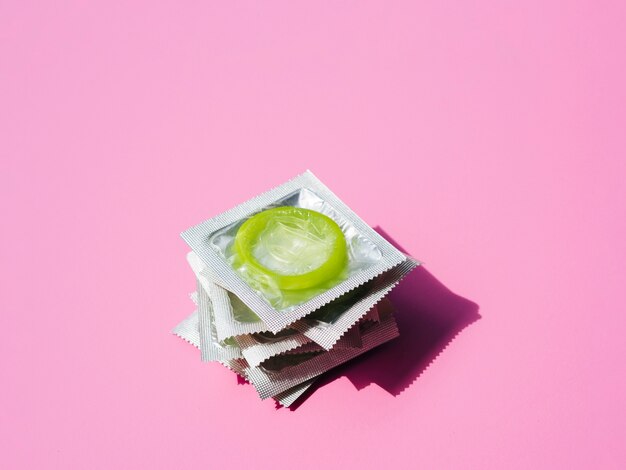 High angle pile of condoms on pink background