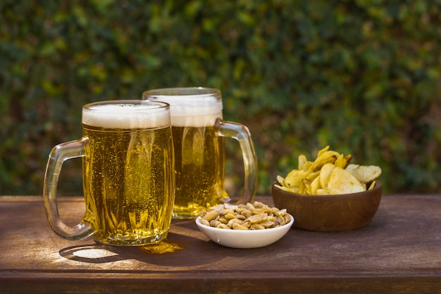 High angle pints with beer and snacks on table