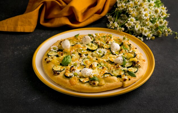 High angle of pizza on plate with chamomile flowers