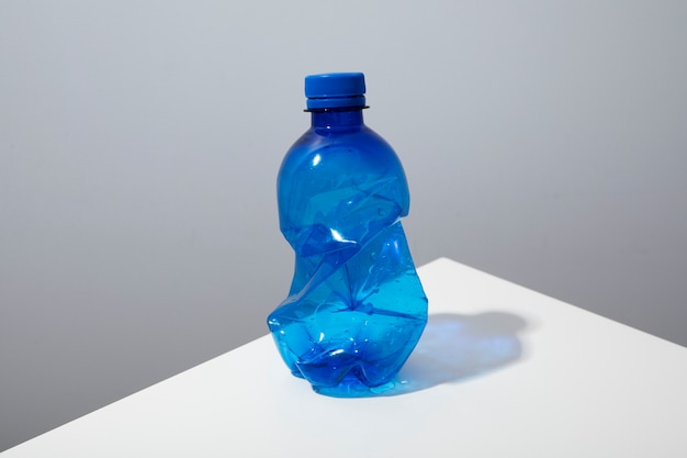 Пластиковая бутылка под большим углом на белом столе