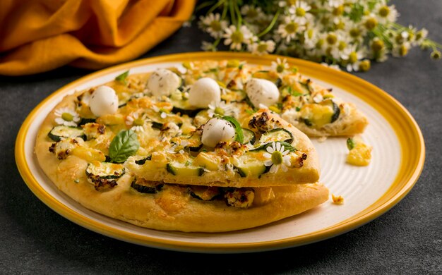 High angle of plate of pizza with chamomile flowers
