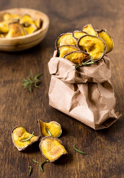 High angle of potato chips in paper bag with rosemary