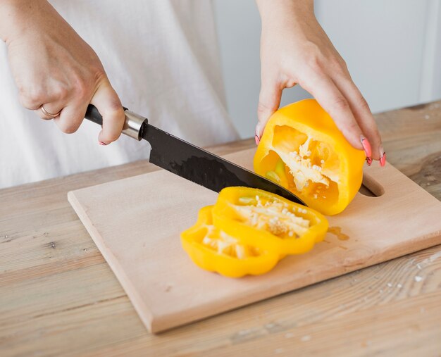 High angle pregnant woman cutting a yellow pepper