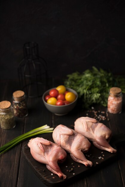 Высокий угол сырой курицы на деревянной доске с ингредиентами