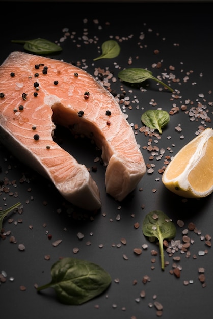 Free photo high angle raw salmon steak with pepper and lemon