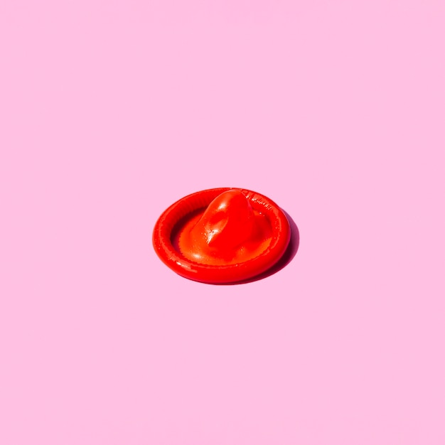 ピンクの背景に高角度の赤いコンドーム