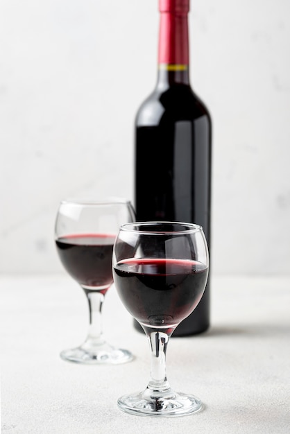 High angle red wine in glasses beside bottle