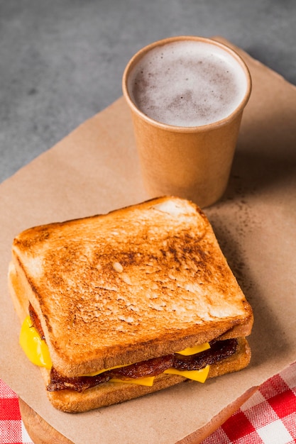 High angle sandwich with bacon and cheese with coffee