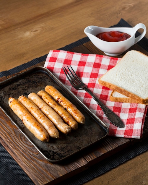 Free photo high angle sausages on tray with bread