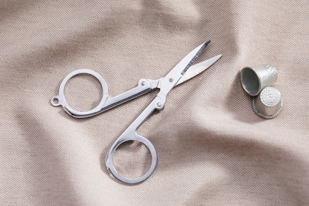 Free photo high angle of scissors with thimbles on textile