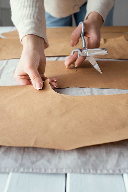 High angle of seamstress using scissors to cut fabric