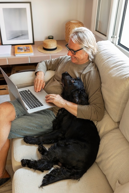 Free photo high angle senior man with dog on couch