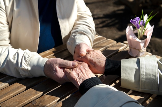 Пожилые люди под высоким углом держатся за руки