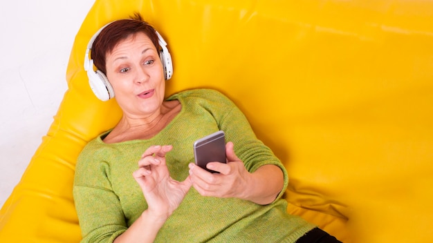 High angle senior woman laid listening music