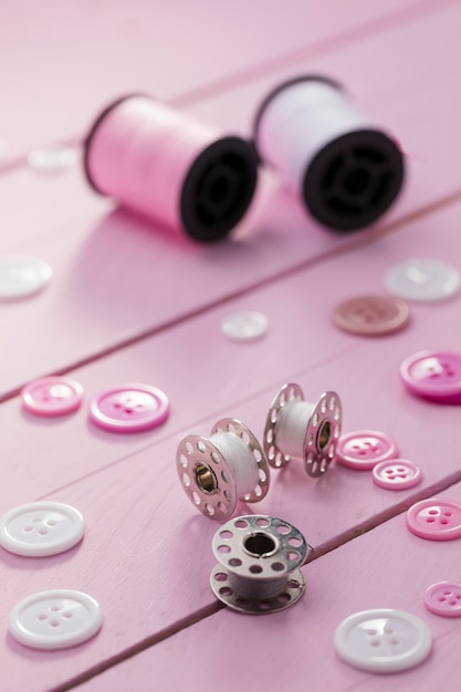 Free photo high angle of sewing machine shuttles with buttons and thread