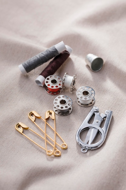 Free photo high angle of sewing machine shuttles with scissors and safety pins