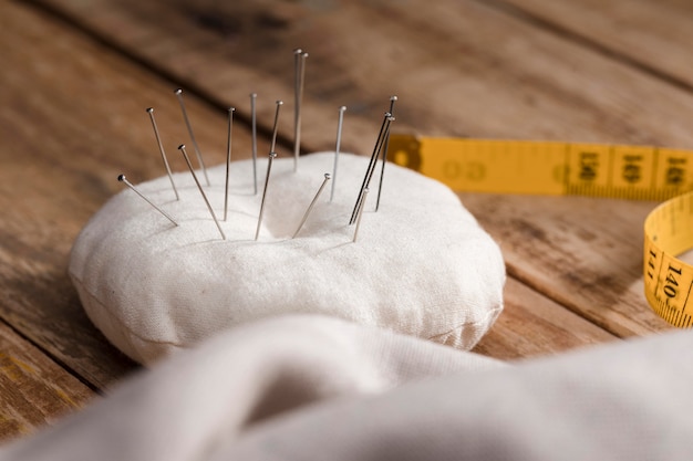 Free photo high angle of sewing needles with measuring tape