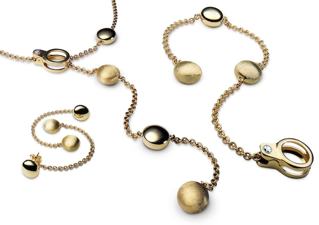 Высокоугольный снимок красивого золотого ожерелья, браслета и серьги на белой поверхности