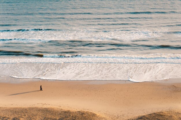 High angle shot of a beautiful wavy ocean against a brown sand