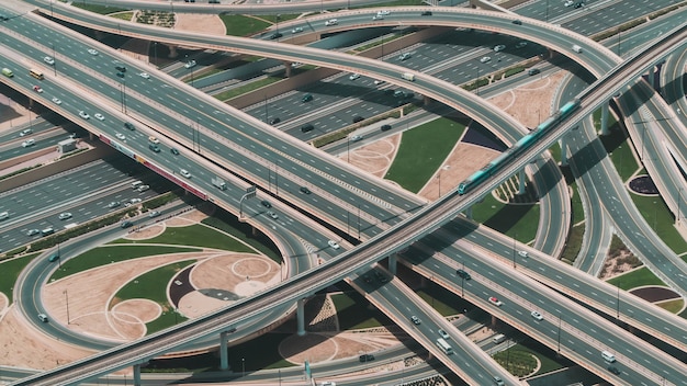 High angle shot of a big highway with multiple roads and a train riding through the central road