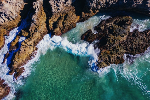 昼間に海の波で覆われた大きな岩のハイアングルショット