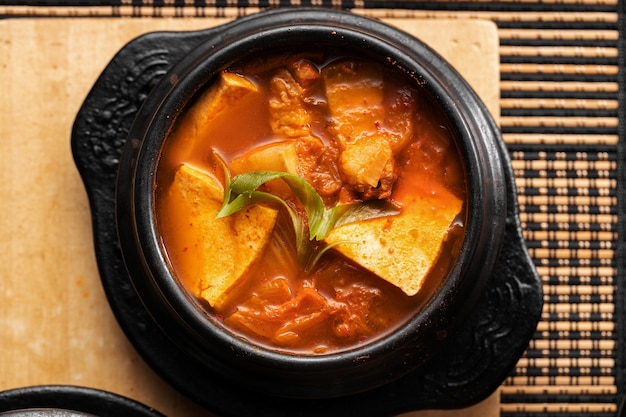 High angle shot of a bowl of delicious vegetable and potato soup on a wooden table