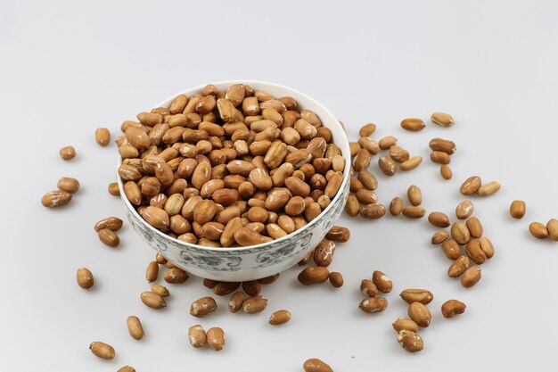 High angle shot of a bowl of peanuts on a white surface