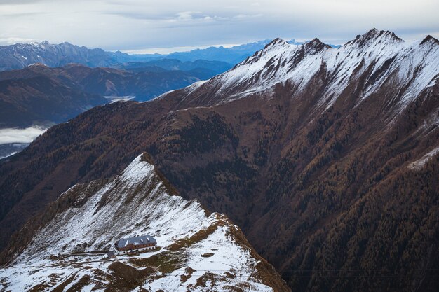 High angle shot of a building on top of a snowy mountain under a cloudy sky