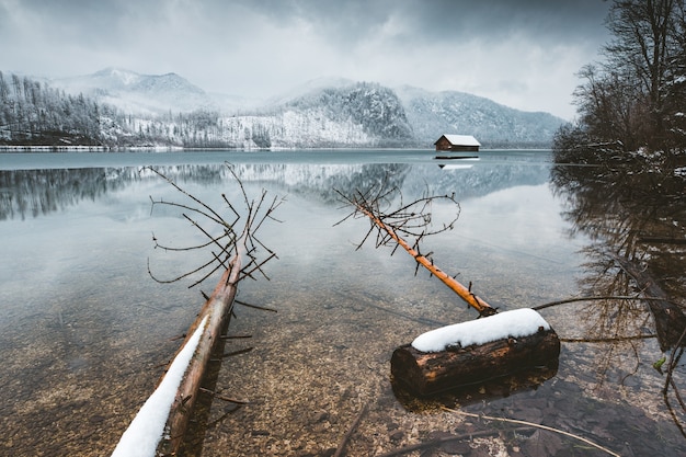 Foto gratuita colpo di alto angolo di un lago calmo con colline sotto un cielo nebbioso