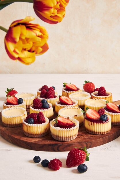 Снимок сырных кексов с мармеладом и фруктами на деревянной тарелке под высоким углом