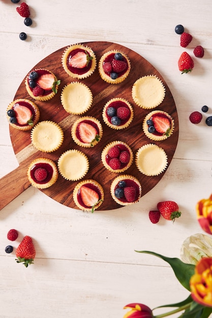 Снимок сырных кексов с мармеладом и фруктами на деревянной тарелке под высоким углом