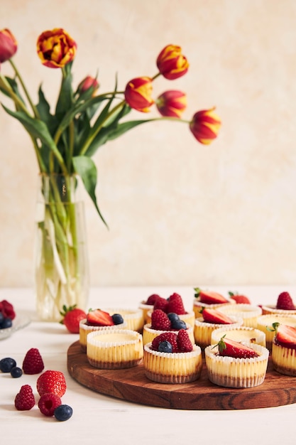 High angle shot of cheese cupcakes with fruit jelly and fruits on a wooden plate