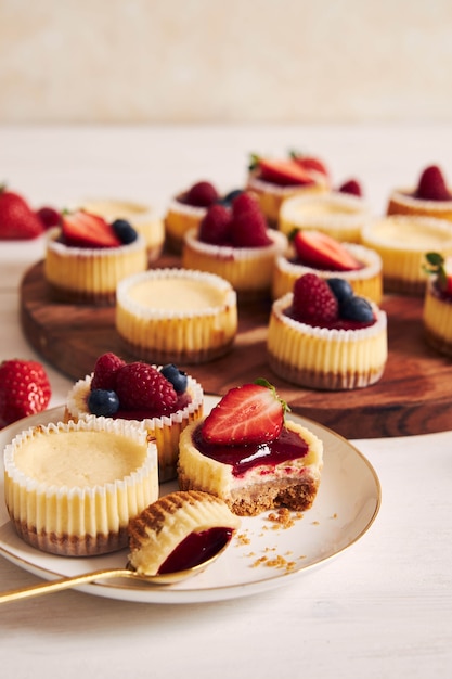 High angle shot of cheese cupcakes with fruit jelly and fruits on a wooden plate