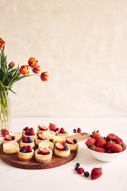 High angle shot of cheese cupcakes with fruit jelly and fruits on a wooden plate