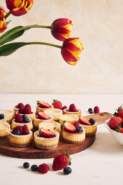 High angle shot of cheese cupcakes with fruit jelly and fruits on a wooden plate