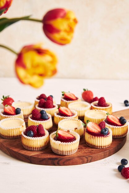 High angle shot of cheese cupcakes with fruit jelly and fruits on a wooden plate