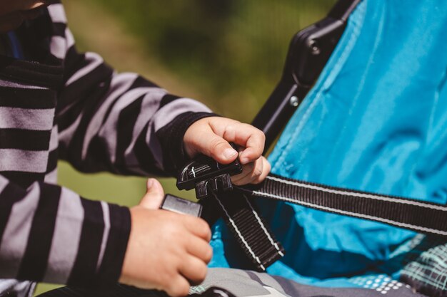 High angle shot of a child fixing his blue car seat captured on a sunny day