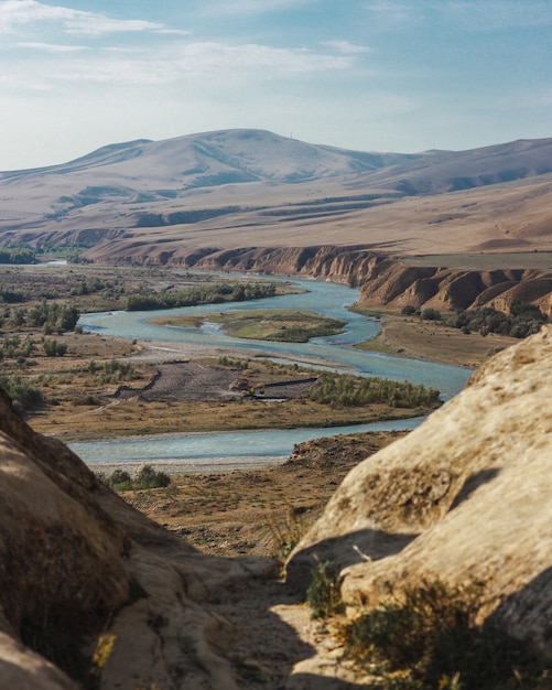 Free photo high angle shot of a curvy river surrounded by high mountains under the cloudy sky