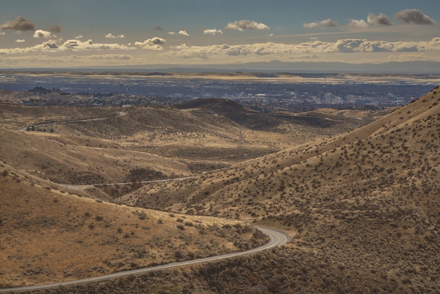 Free photo high angle shot of a curvy road in the middle of mountains with city buildings in the distance