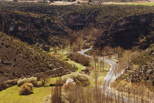 High angle shot of a curvy road surrounded by rocky cliffs and beautiful greenery