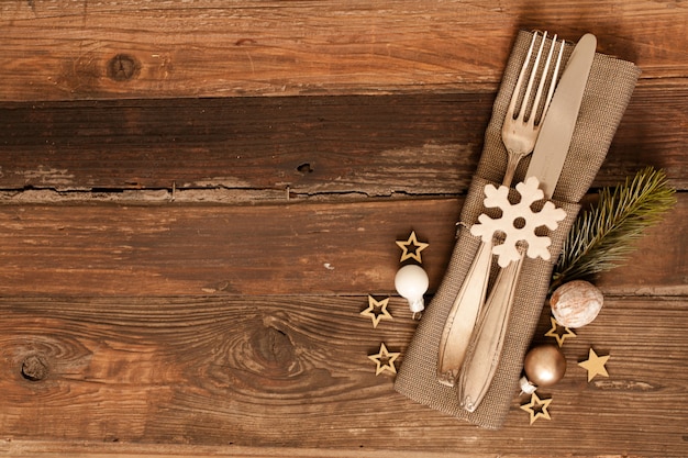 High angle shot of cutlery set with country style napkin and Christmas decoration on wooden surface