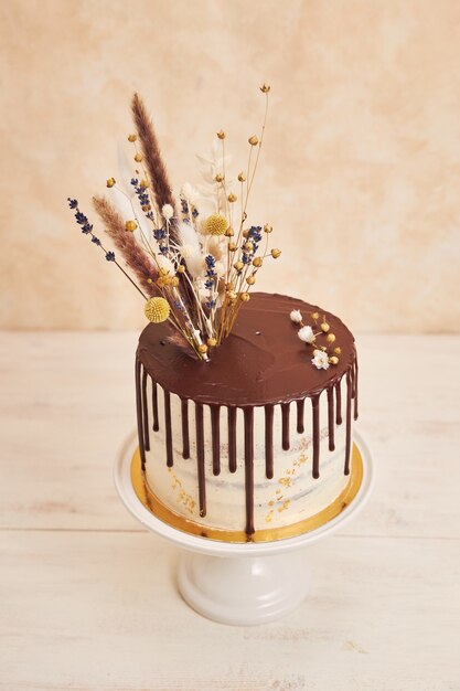 초콜릿 드립과 황금 장식이 있는 꽃을 곁들인 맛있는 보헤미안 케이크의 하이 앵글 샷