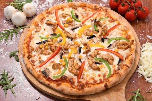 High angle shot of a delicious pizza with colorful bell peppers, corn, meat and mushrooms