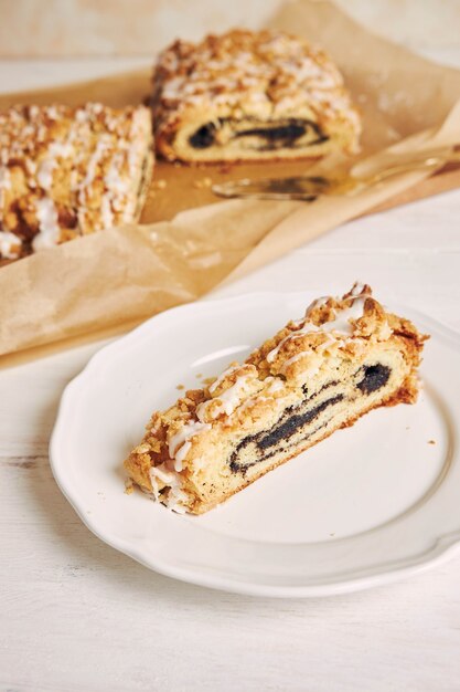 High angle shot of delicious poppy seeds piece of cake with a white sugar glaze on a white table